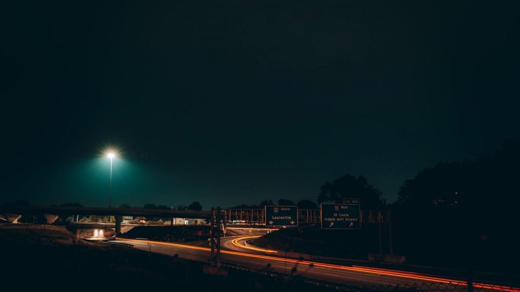 Captivating long exposure shot of Indianapolis highway at night with light trails and road signs.